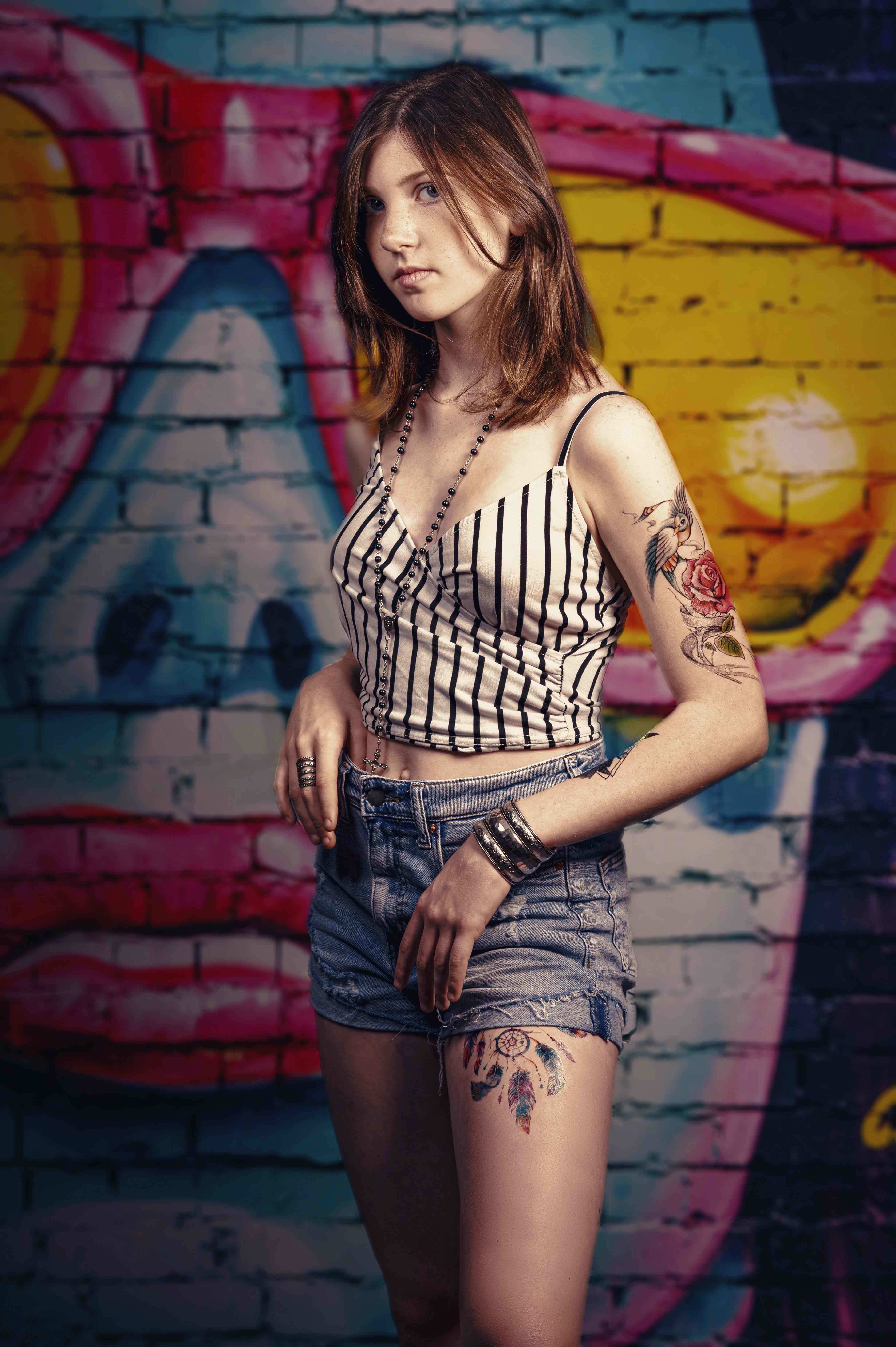 Photo de mode à Agen : tatouages et tenue moderne devant fresque murale